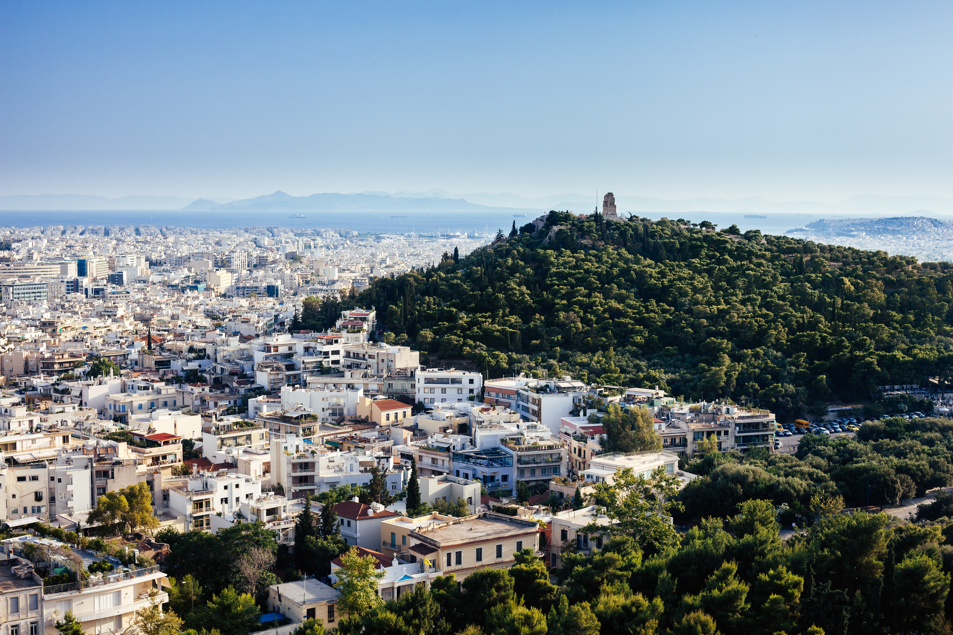 View of Athens from Lycabettus Hill in the City Center. Clear sky shows view of sea in South Athens and islands in Saronic Gulf.