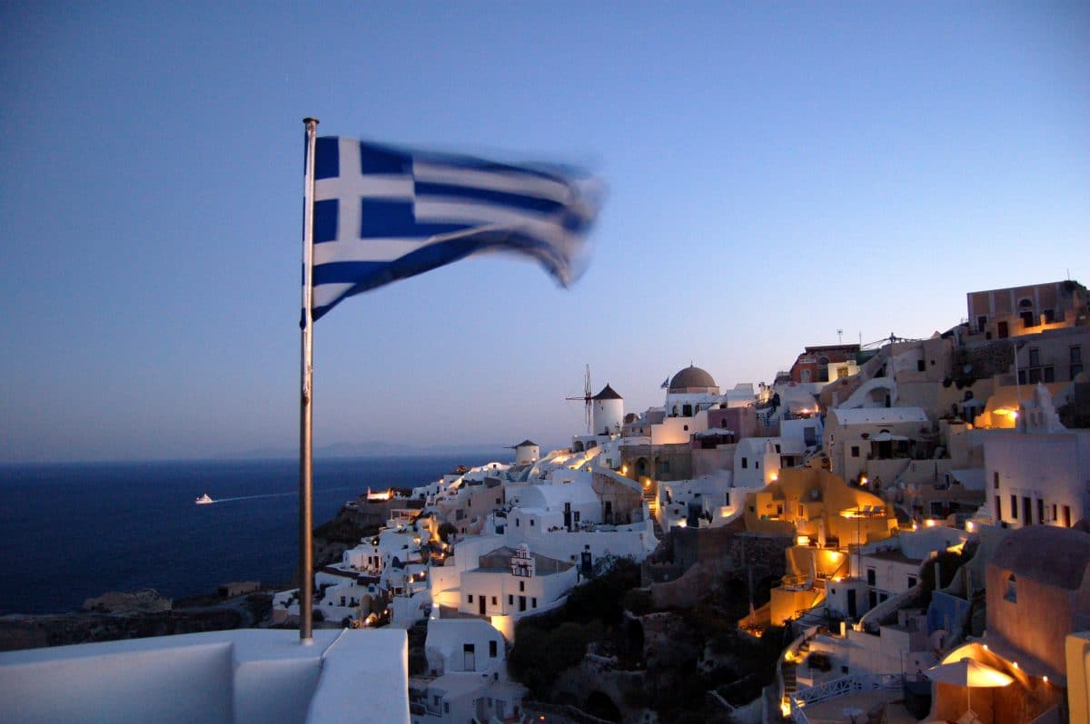 Santorini at night, with a Greek flag in the foreground