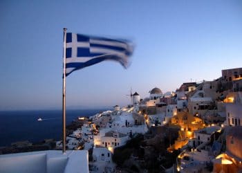 Santorini at night, with a Greek flag in the foreground