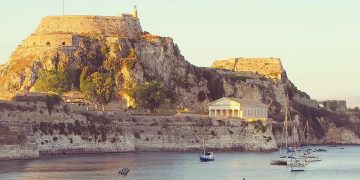 Corfu, Kerkira in the Ionian islands in Greece. View from a quiet beach, overlooked by a castle, the Old Fortress, and a temple.