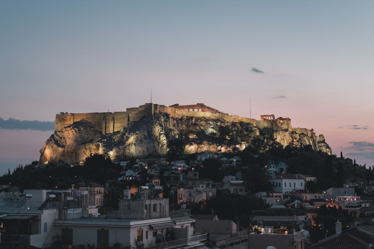 Night view of the Acropolis rock in Athens during sunset. The lights on the rock are illuminating the Parthenon temple.